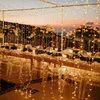 A beautifully decorated outdoor table setting at dusk, illuminated by numerous string lights. Produktbild-Vorschau