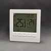 A white digital thermostat with a green LCD screen displaying temperature and time, placed on a gray textured surface. Podgląd zdjęcia produktu