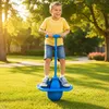 Junger Junge spielt fröhlich mit einem blauen Pogo-Ball in einer grasigen Parkumgebung an einem sonnigen Tag Podgląd zdjęcia produktu
