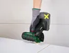 A person wearing a glove is using a cordless angle grinder to cut a tile. Produktbild-Vorschau