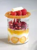 A dessert in a glass jar, topped with raspberries and a white chocolate curl. Náhled obrázku produktu