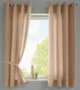 A window with beige curtains drawn to the sides, revealing a view of trees and sky. Produktbild-Vorschau