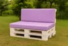 A pallet sofa with purple cushions sits on a grassy lawn with trees in the background. Produktbild-Vorschau