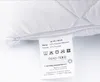 A close-up of a product label attached to a white quilted fabric, likely a pillow or cushion. Náhľad obrázku produktu