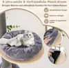 A cat is resting on a plush cushion on a wooden platform, part of a cat tree. Inset images show how the cushion is attached and removed. Produktbild-Vorschau