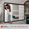 A woman is organizing clothes inside a large sliding door wardrobe in a bedroom. Produktbild-Vorschau