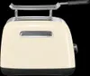A cream-colored KitchenAid toaster with a chrome rack on top, set against a black background. Produktbild-Vorschau
