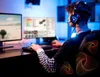 A person wearing headphones is playing a video game on a computer. Anteprima dell’immagine prodotto