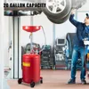 A mechanic is working on a car in a garage, with a red oil drain tank in the foreground. Náhled obrázku produktu