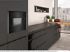 A modern kitchen scene featuring a built-in black microwave and dark gray cabinets. Náhľad obrázku produktu