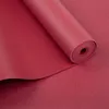 A rolled-up yoga mat in a deep red color, with a textured surface. Produktbild-Vorschau