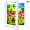 A white frame holding two open pages of a colorful drawing of a hamburger house. Produktbild-Vorschau