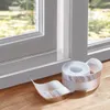 A roll of sealing tape is placed on a wooden floor next to a window frame. Náhľad obrázku produktu
