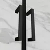 A close-up view of black shower door handles against a marble-like background. Produktbild-Vorschau
