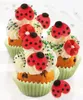 A close-up of several ladybug-themed cupcakes, decorated with white frosting, green and black sprinkles, and red fondant ladybugs and flowers. Anteprima dell’immagine prodotto