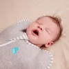 A close-up shot of a baby swaddled in a grey Love to Dream swaddle. Produktbild-Vorschau