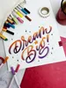 A flat lay of art supplies and a handwritten motivational quote. Voir les images du produit