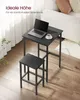 A black bar table and two bar stools are set up in a living room area, with a laptop and coffee cup on the table. Produktbild-Vorschau