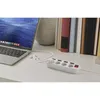 A laptop, earphones, and a power strip are arranged on a desk with books in the background. Produktbild-Vorschau