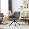 A dark gray swivel armchair is placed in a living room setting, next to a cream-colored armchair and a wooden side table with a lamp and a cup. Produktbild-Vorschau