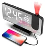 A digital alarm clock with a projected display and a smartphone charging next to it. Produktbild-Vorschau