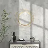A decorative wall mirror with a gold frame is displayed on a concrete wall above a cabinet. A plant is to the left, and decorative objects are on the cabinet. Náhľad obrázku produktu