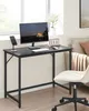 A black desk with a computer, keyboard, mouse, and phone is set up in a room with a window and a couch. Náhled obrázku produktu