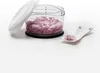 A clear shot of a manual chopper filled with chopped red onions, with a lid and a small spoon with onions on the side, all on a white background. Produktbild-Vorschau