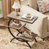 A C-shaped side table with three shelves is placed next to a sofa, displaying decorative items and books. Voir les images du produit