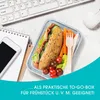 A lunchbox with a sandwich and vegetables on a desk next to a keyboard and phone. Voir les images du produit