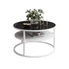 A round coffee table with a black glass top and a white shelf below, decorated with a vase of flowers and a bowl of fruit. Produktbild-Vorschau