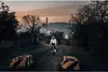 A person rides a bicycle on a dirt path with industrial structures in the background during dusk. Náhľad obrázku produktu