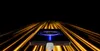 A smartphone is charging with a glowing effect on its screen, set against a background of streaking golden lights. Produktbild-Vorschau
