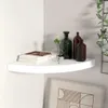 A white corner shelf with decorative items on it, including books and glass bottles. Voir les images du produit
