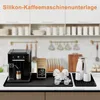 A coffee machine and accessories are arranged on a countertop in a kitchen setting. Produktbild-Vorschau