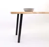A close-up view of a table with black legs and a wooden top, with a gray bowl on top. Produktbild-Vorschau