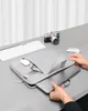 A person's hands are shown placing a laptop into a gray laptop sleeve on a gray desk. A keyboard, mouse, and camera are also visible on the desk. Anteprima dell’immagine prodotto