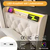 A close-up of a white upholstered headboard with integrated LED lighting and charging ports. Náhľad obrázku produktu