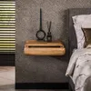 A wooden nightstand with decorative items next to a bed. Produktbild-Vorschau
