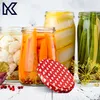 A collection of jars filled with preserved vegetables, including carrots, cauliflower, and green beans, with a decorative lid in the foreground. Podgląd zdjęcia produktu