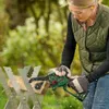 A woman is using a cordless chainsaw to cut a piece of wood on a sawhorse outdoors. Podgląd zdjęcia produktu