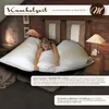 A woman is lying on a large, fluffy white duvet in a bedroom setting. Produktbild-Vorschau