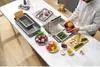 A person is preparing vegetables in a kitchen sink area, with various kitchen accessories and ingredients laid out on a white countertop. Voir les images du produit
