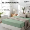 A bedroom scene with a bed made with a green fitted sheet and a knitted throw. Produktbild-Vorschau