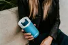 A person holding a blue Kambukka thermobottle outdoors. Náhled obrázku produktu