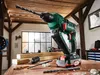 A cordless hammer drill with accessories is displayed on a wooden workbench in a workshop setting. Produktbild-Vorschau