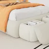 A close-up view of a bed with an orange blanket and storage ottomans. Produktbild-Vorschau