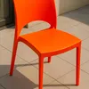 An orange plastic chair is shown outdoors on a tiled patio. Voir les images du produit