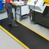A person stands on an anti-fatigue mat in a workshop setting. Produktbild-Vorschau