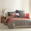 A neatly made bed with striped bedding and pillows. Produktbild-Vorschau